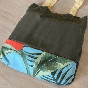 Bag with light yellow straps, deep green body with a panel of blue tropical fabric at the bottom